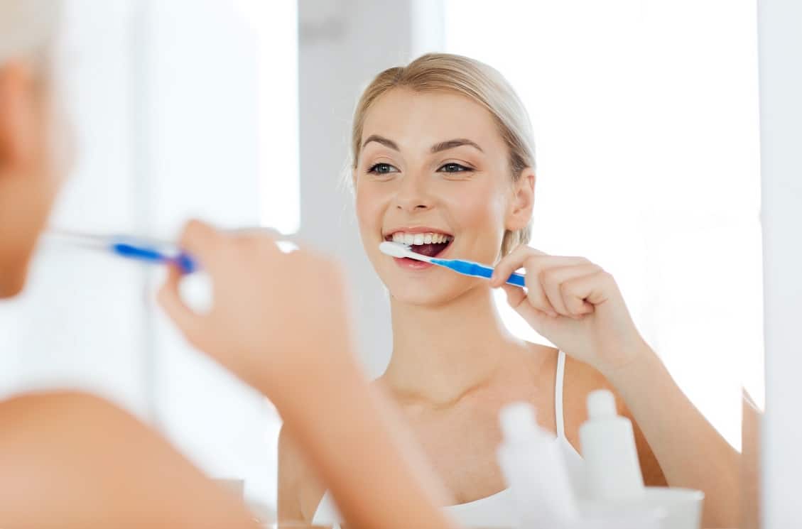 West Hartford CT Dentist Woman Brushing Her Teeth in the Mirror